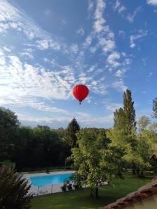 ein roter Ballon am Himmel über einem Pool in der Unterkunft Ecrin d' Amour in Castels