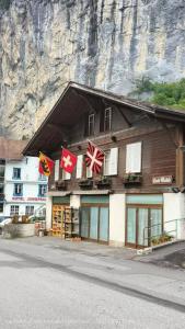 a building with flags in front of a mountain at Chalet Maithili Lauterbrunnen -152-Year-Old Majestic Chalet in Lauterbrunnen