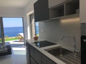 a kitchen with a sink and a view of the ocean at Villa Avra in Ierápetra +10 photos