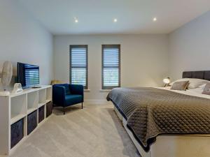 a bedroom with a bed and a tv and a blue chair at 2 Bed in Sandown 89291 in Sandown