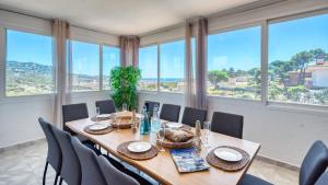 a dining room with a table and chairs and windows at Costacabana - Villa Abigail in Lloret de Mar