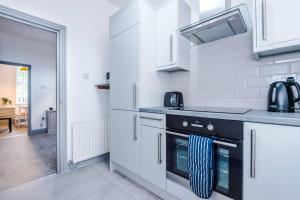 a kitchen with white cabinets and a black oven at 5 Sleeper LFC Themed Apartment in Liverpool