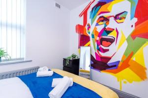 a bedroom with a bed with a painting on the wall at 5 Sleeper LFC Themed Apartment in Liverpool