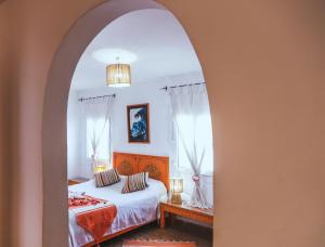 ein Schlafzimmer durch einen Torbogen mit einem Bett in der Unterkunft Dar Nafoura-Mogador in Essaouira