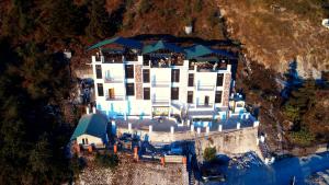an aerial view of a large white building on a mountain at The Whispering Pine and Suites in Mussoorie