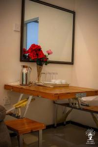 una mesa con un espejo y un jarrón de flores. en Arcadea Eco Lodge, 