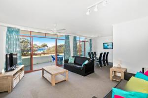 a living room with a couch and a tv at Perfectly Positioned Across From Mollymook Beach in Mollymook