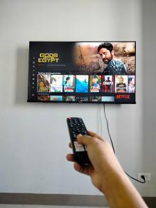 a person holding a remote control in front of a tv at Sea Residences, S, Shell Janine's Residency in Manila