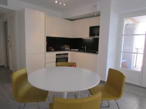 a white table and yellow chairs in a kitchen at New development Place des Lices in Saint-Tropez