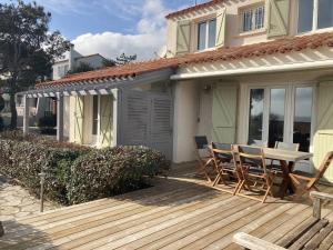 a wooden deck with chairs and a table on a house at Villa de grand standing les Garrigues in Narbonne-Plage