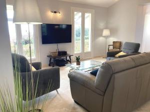 a living room with a couch and a flat screen tv at Villa de grand standing les Garrigues in Narbonne-Plage