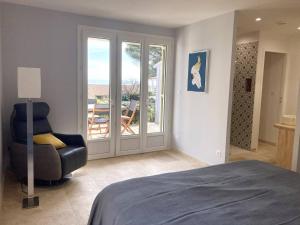a bedroom with a bed and a chair and a balcony at Villa de grand standing les Garrigues in Narbonne-Plage