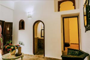 un couloir avec une table et un vase de fleurs dans l'établissement Dar Nafoura-Mogador, à Essaouira