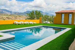 a swimming pool with lawn chairs and a house at Félix Romero II in Castril