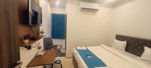 a room with a bed and a desk and a tv at WELCOME VISTA in Navi Mumbai
