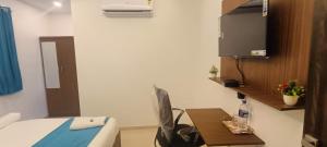 a room with a bed and a tv and a table at WELCOME VISTA in Navi Mumbai +1 photo