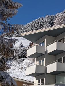 ein Gebäude mit Balkonen und schneebedeckten Bäumen in der Unterkunft Haus Zervreila in Vals