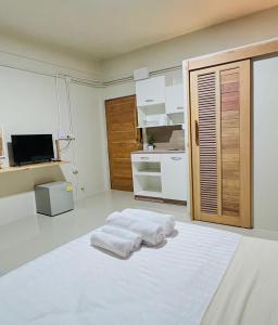 a white room with three towels on a bed at Muji Hotel KrabI in Krabi
