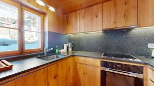 a kitchen with wooden cabinets and a sink and a window at Family chalet in the heart of the Val d'Anniviers in Saint-Luc