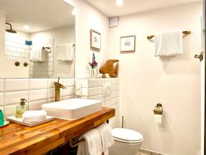 La salle de bains blanche est pourvue d'un lavabo et de toilettes. dans l'établissement Le Mas de Caroline, à Gargas
