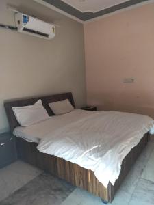 uma cama com lençóis brancos e almofadas num quarto em HOTEL CASTLE HOME STAY em Jaipur