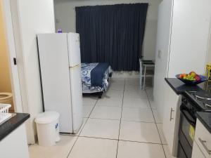 eine Küche mit einem Kühlschrank und ein Zimmer mit einem Bett in der Unterkunft Kiaatplace Holiday Apartment in Kingsborough