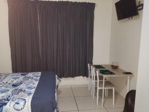 a bedroom with a bed and a desk and a table at Kiaatplace Holiday Apartment in Kingsburgh