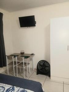 a room with a table and a tv on the wall at Kiaatplace Holiday Apartment in Kingsburgh