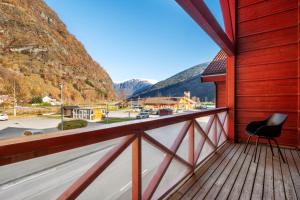 a chair on a balcony with mountains in the background at Flåm Station Apartments in Flåm