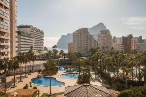 a city with two pools and palm trees and buildings at Apartamento Coral Beach - PlusHolidays in Calpe