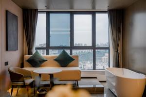 a living room with a couch and a table and a large window at Yunmu Hotel Luzhou in Luzhou