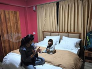 een vrouw en een kind op een bed bij Hotel Sai Kripa , Ravangla in Ravangla