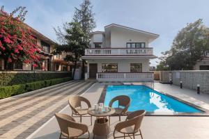 a house with a swimming pool with chairs and a table at StayVista's Brookvale Cottage - Dive into tranquility with pool view and gazebo in Lonavala