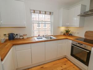 een keuken met witte kasten, een wastafel en een raam bij 7A Lansdown Place Lane in Cheltenham