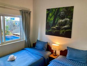 a bedroom with two beds and a painting of a buddha at Lotus Haven Villa in Siem Reap