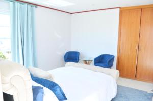 1 dormitorio con 1 cama y 2 sillas azules en BellMatt - Table Mountain and Ocean View Guests Suites, en Ciudad del Cabo