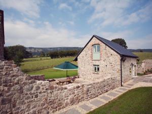 um edifício de pedra com uma mesa e um guarda-chuva verde em 2 Bed in Abergavenny 42909 em Mamhilad