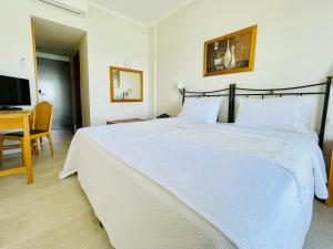 a bedroom with a large white bed and a television at Studios Afitos in Afitos