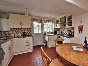a kitchen with white cabinets and a wooden table at 2 Bed in Eyam PK812 in Eyam