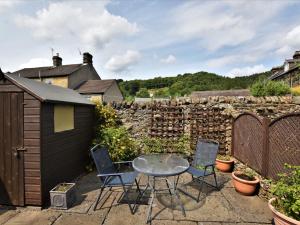 a patio with a table and chairs and a stone wall at 2 Bed in Eyam PK812 in Eyam