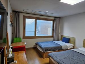 a room with two beds and a table and a window at Samda Hostel in Jeju
