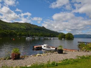 a boat is docked in the water on a lake at 1 Bed in Callander 45288 in Saint Fillans