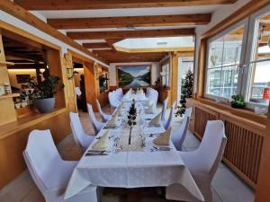 a long dining room with a long table and white chairs at Fischerhof Glinzner Hotel-Restaurant-Camping in Afritz