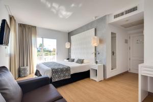 a hotel room with a bed and a couch at Cala Millor Garden Hotel - Adults Only in Cala Millor