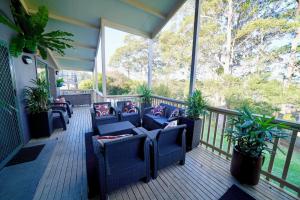 a screened in porch with blue chairs and plants at Quay Largo in Lake Tabourie