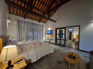 a bedroom with a large bed and a living room at Hoi An Ancient House Resort & Spa in Hoi An