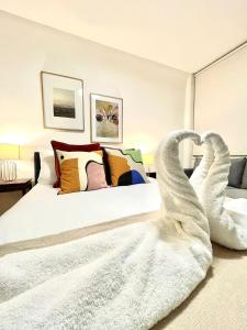 kings cross St Pancras luxury apt في لندن: غرفة نوم مع سرير بجعتين مصنوعة من المناشف