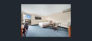 Un dormitorio con una cama y una mesa y sillas. en Gladstone Capricorn Apartments, en Gladstone