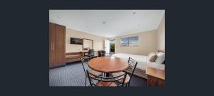 a living room with a table and a bed at Gladstone Capricorn Apartments in Gladstone