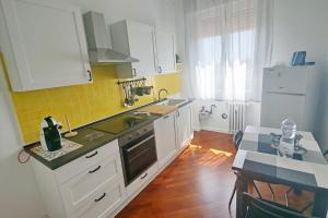 A casa di nonna Marisa في بارما: مطبخ به دواليب بيضاء وبلاط اصفر على الحائط